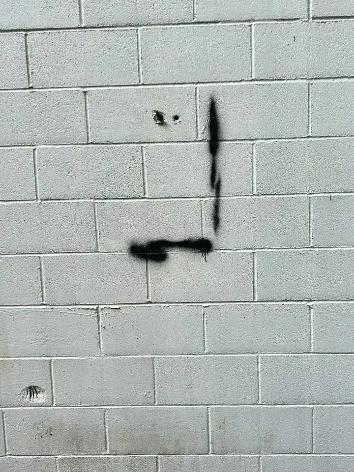 The same wall the next day: the painting is gone, and a spray-painted black corner mark is left where the frame hung